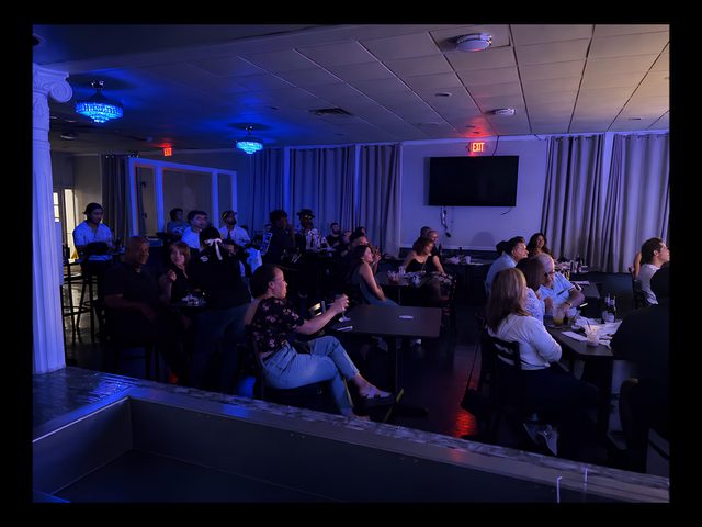 A full room watches a JR Global Productions show, performer on stage under the lights